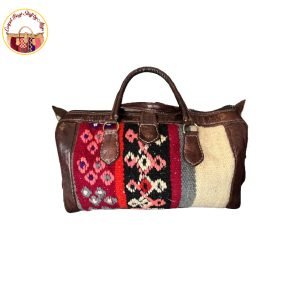 Kashmir-inspired carpet bag featuring colorful floral patterns in shades of red, blue, and yellow, set against a neutral background.